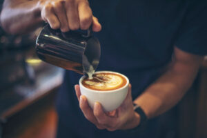 Close-up of a barista pouring steamed milk to create intricate latte art, showcasing premium wholesale Ethiopian coffee UK quality.