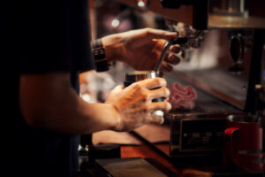 Barista steaming milk in a pitcher for a latte using wholesale Ethiopian coffee UK.