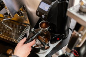A high-angle view of a barista grinding fresh beans into a portafilter for wholesale Ethiopian coffee UK.