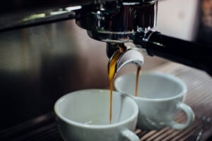 Close-up of rich espresso pouring from a machine into two white ceramic cups, ideal for wholesale Ethiopian coffee UK suppliers.