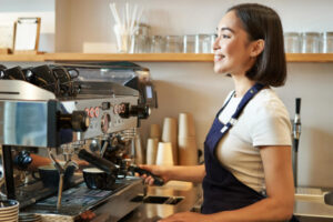 A smiling barista preparing a drink using a professional espresso machine, highlighting wholesale Ethiopian coffee UK quality.